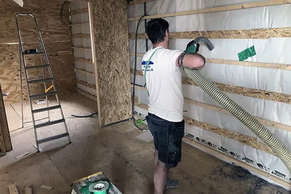 Construction Worker Insulating Wall with Fiberglass Batt